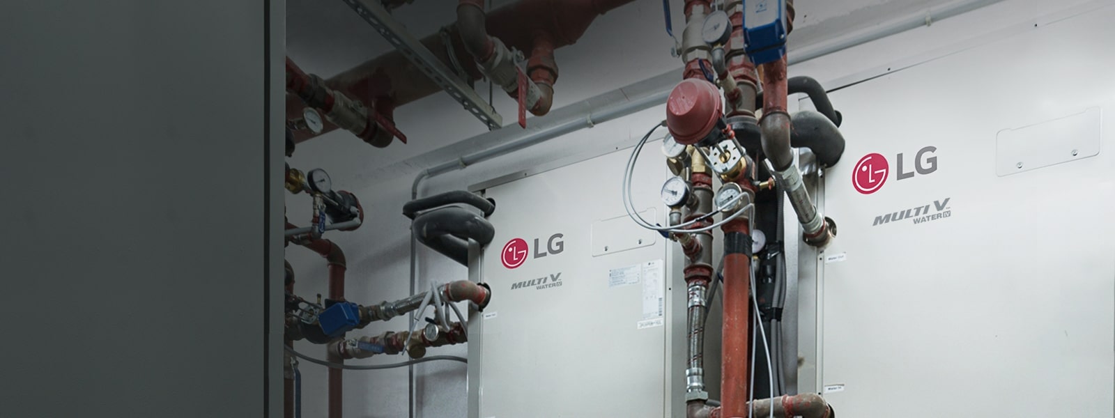 Two Multi V Water IV units with a complex network of black and red piping in a mechanical room.